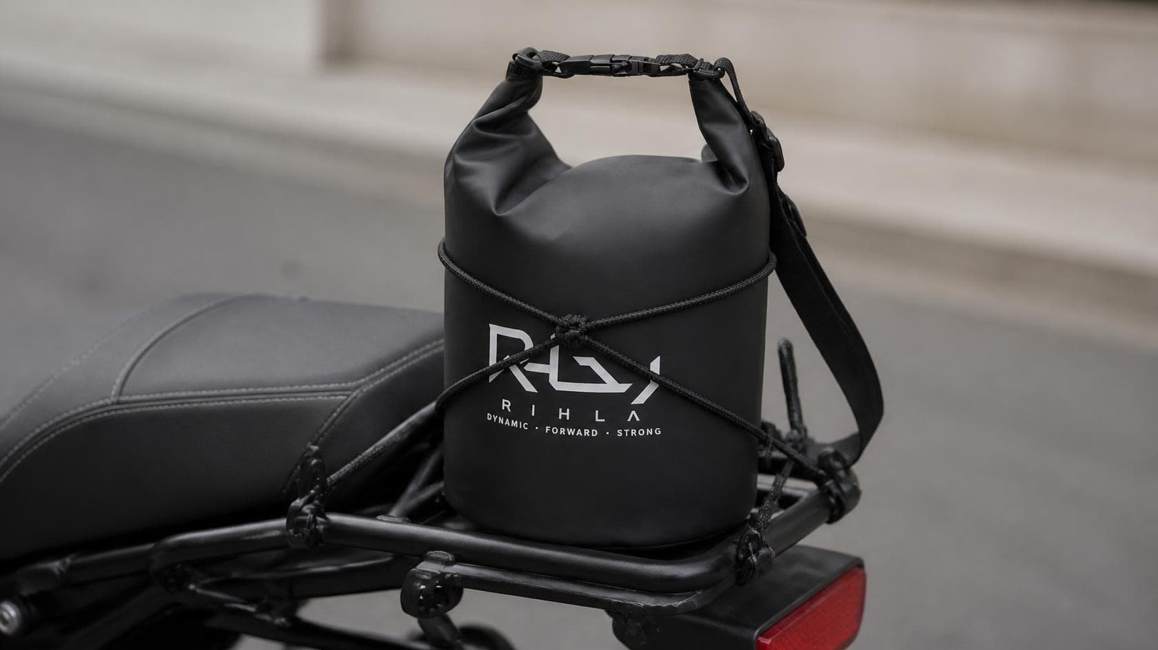 Hands rolling closed a black waterproof roll-top dry bag with buckle